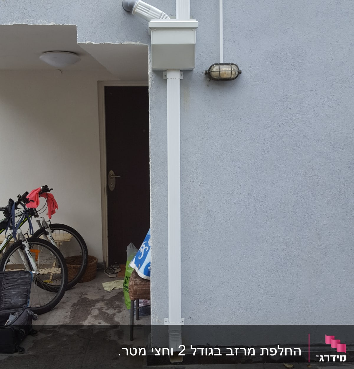 מרזב לבן מחובר לקיר אפור